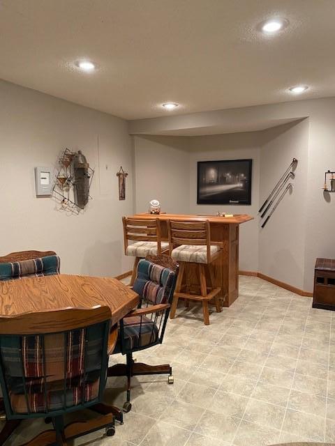 interior space with recessed lighting, a bar, and baseboards