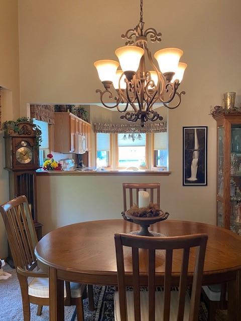 carpeted dining room with an inviting chandelier