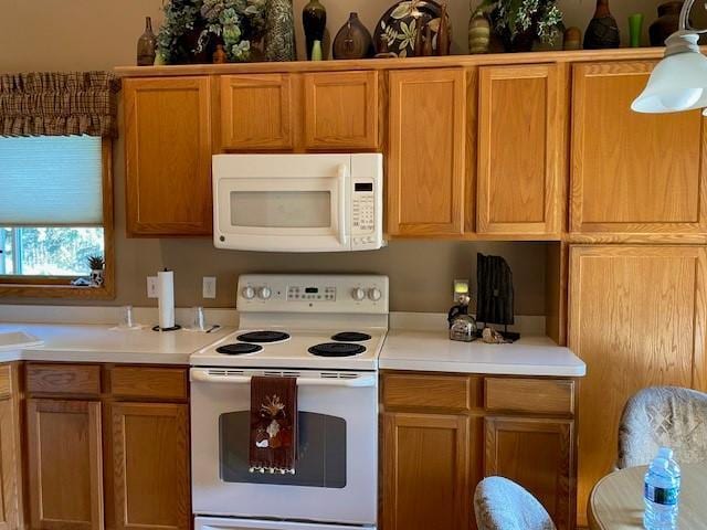 kitchen featuring brown cabinetry, white appliances, and light countertops