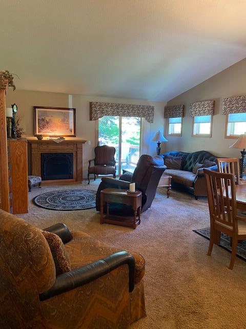 carpeted living room featuring lofted ceiling and a fireplace