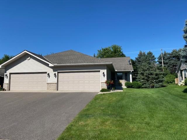 ranch-style house with brick siding, an attached garage, driveway, and a front lawn