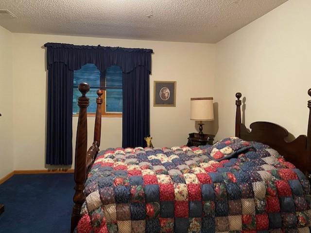 bedroom featuring carpet flooring, baseboards, and a textured ceiling