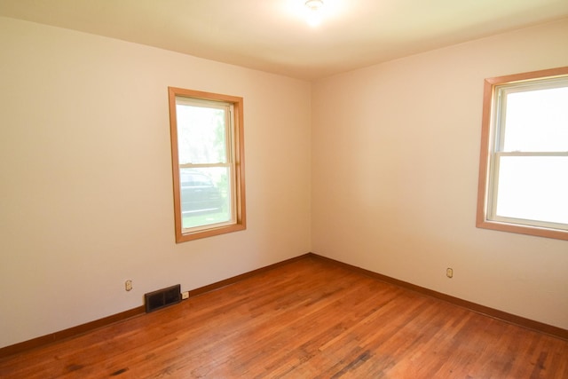 empty room with hardwood / wood-style flooring and plenty of natural light