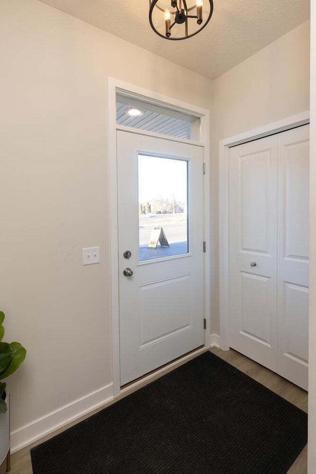 doorway to outside with a notable chandelier