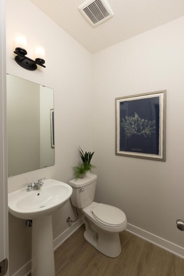 bathroom with toilet and hardwood / wood-style flooring