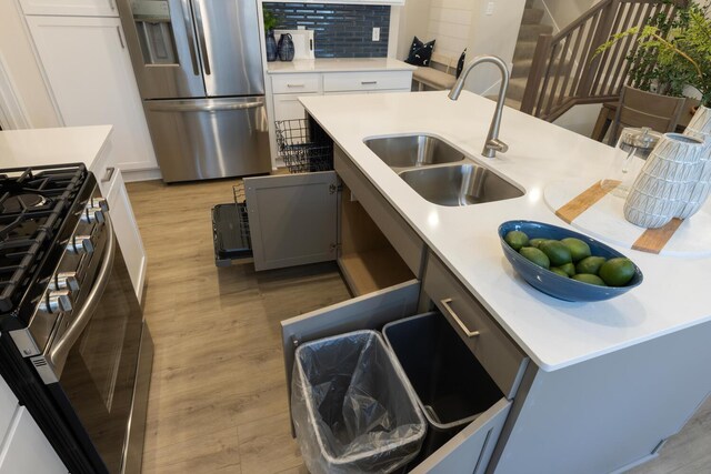 kitchen featuring sink, decorative backsplash, light hardwood / wood-style flooring, and stainless steel appliances