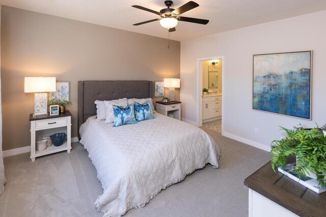 carpeted bedroom with ensuite bathroom and ceiling fan