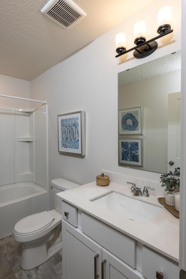 full bathroom with vanity, tile patterned floors, shower / bath combination, toilet, and a textured ceiling