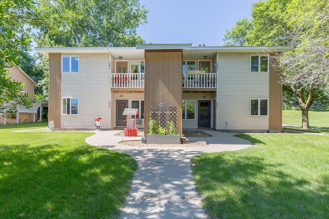 rear view of property with a balcony and a lawn