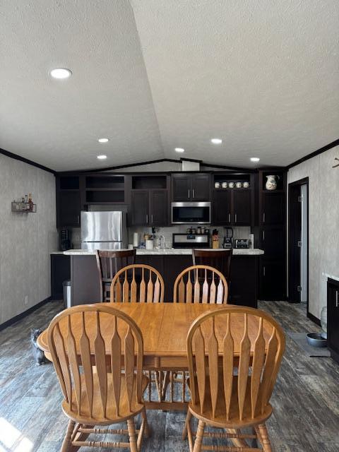 dining room featuring a textured ceiling, dark hardwood / wood-style floors, vaulted ceiling, and ornamental molding