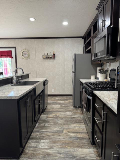 kitchen with hardwood / wood-style floors, sink, stainless steel appliances, and a textured ceiling