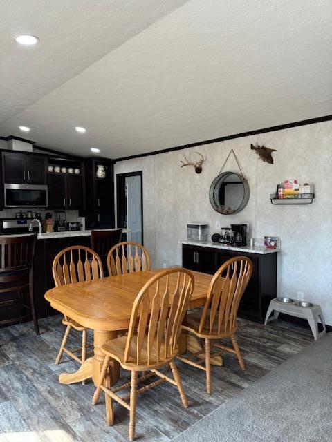 dining room featuring a textured ceiling, dark wood-type flooring, and lofted ceiling