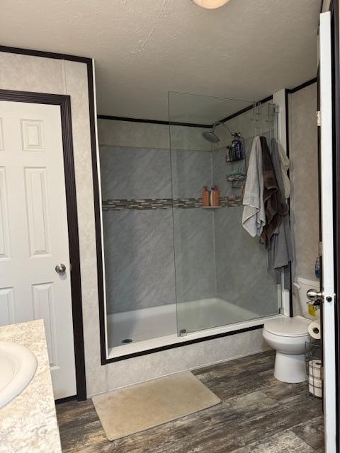 bathroom with hardwood / wood-style floors, vanity, toilet, and a shower with door