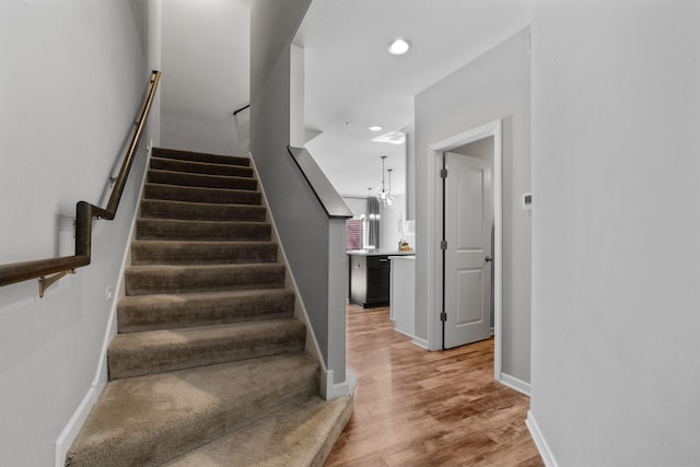 staircase featuring a chandelier and hardwood / wood-style floors