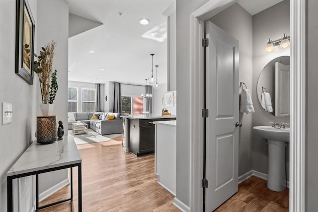 hall featuring light hardwood / wood-style floors, sink, and a notable chandelier