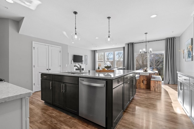 kitchen featuring an island with sink, a notable chandelier, hanging light fixtures, stainless steel dishwasher, and sink