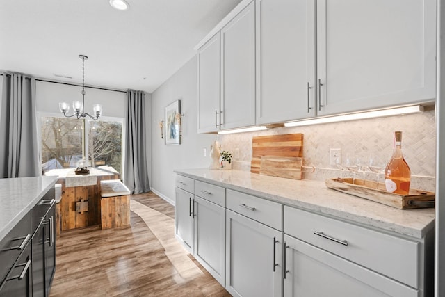 kitchen featuring a notable chandelier, decorative light fixtures, white cabinetry, and light stone countertops