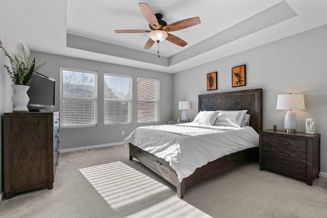 carpeted bedroom featuring ceiling fan and a tray ceiling