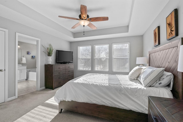 carpeted bedroom featuring ceiling fan, connected bathroom, and a tray ceiling