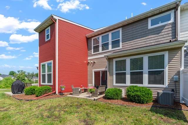 back of property with a patio area, a yard, and central AC