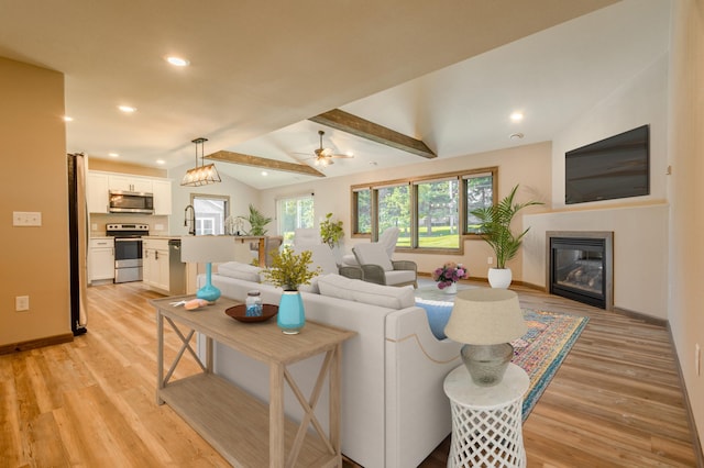 living room with lofted ceiling with beams, recessed lighting, ceiling fan, light wood-style floors, and a glass covered fireplace