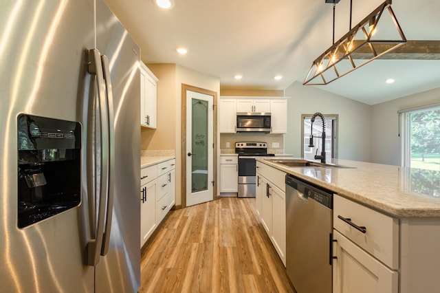 kitchen with light wood finished floors, recessed lighting, a sink, appliances with stainless steel finishes, and white cabinetry
