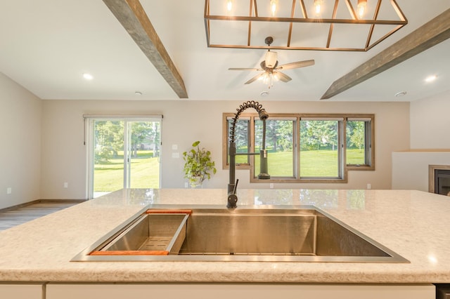 kitchen with a sink, wood finished floors, recessed lighting, baseboards, and ceiling fan