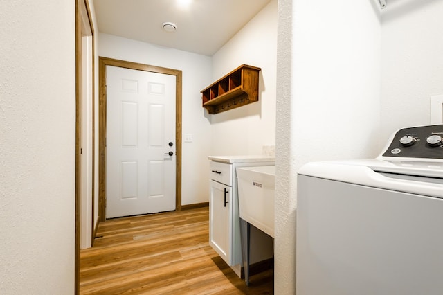 laundry area featuring washer / clothes dryer, cabinet space, and light wood finished floors