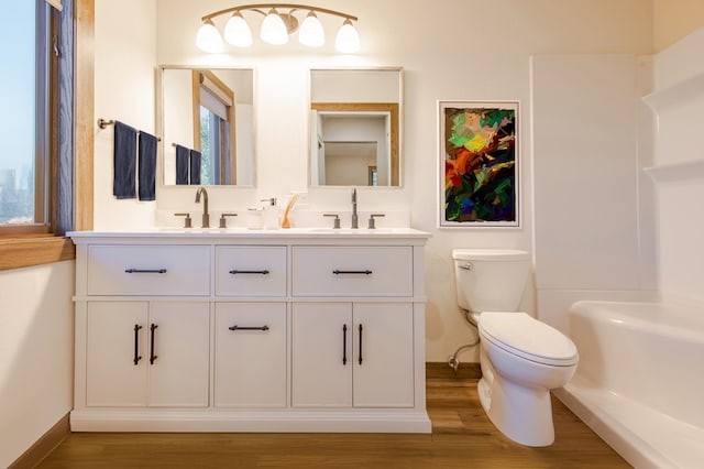 full bathroom with double vanity, wood finished floors, toilet, and a sink