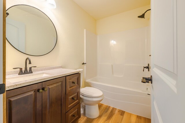 bathroom with vanity, washtub / shower combination, toilet, and wood finished floors