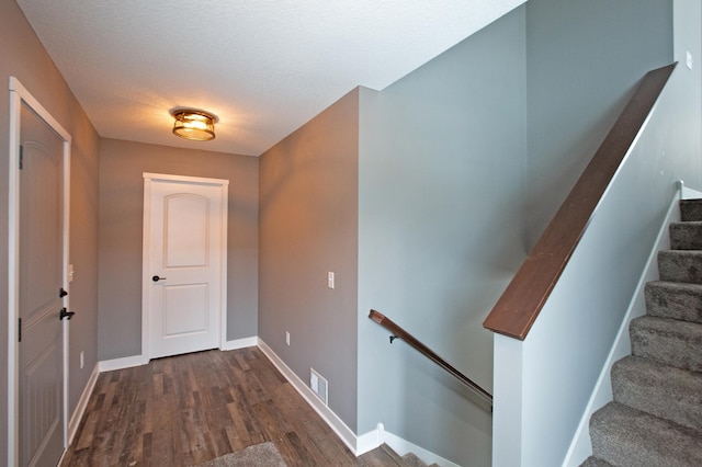 doorway featuring a textured ceiling and dark wood-type flooring