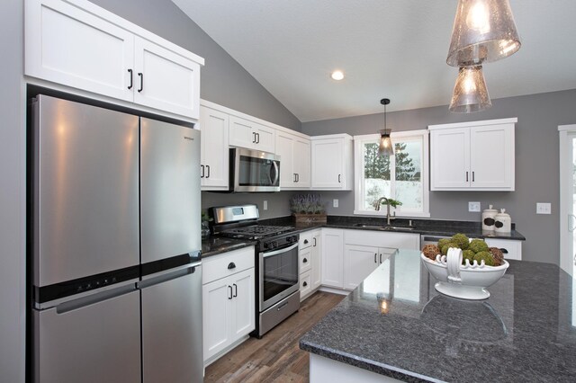 kitchen featuring white cabinets, dark hardwood / wood-style flooring, stainless steel appliances, decorative light fixtures, and sink