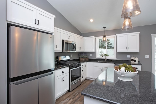 kitchen with sink, white cabinetry, decorative light fixtures, dark stone counters, and stainless steel appliances