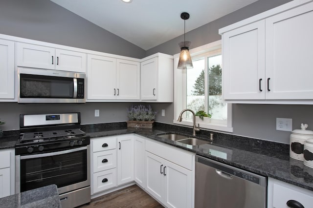 kitchen featuring appliances with stainless steel finishes, decorative light fixtures, white cabinetry, lofted ceiling, and sink