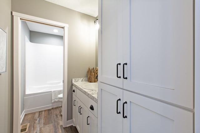 full bathroom featuring hardwood / wood-style flooring, shower / bath combination, toilet, and vanity