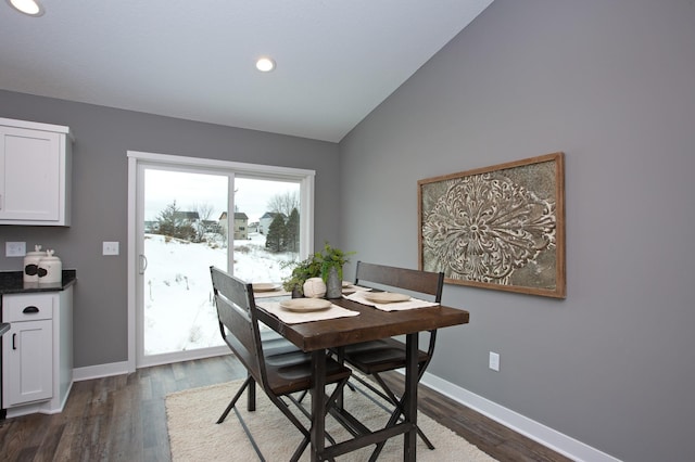 dining space with dark wood-type flooring and vaulted ceiling