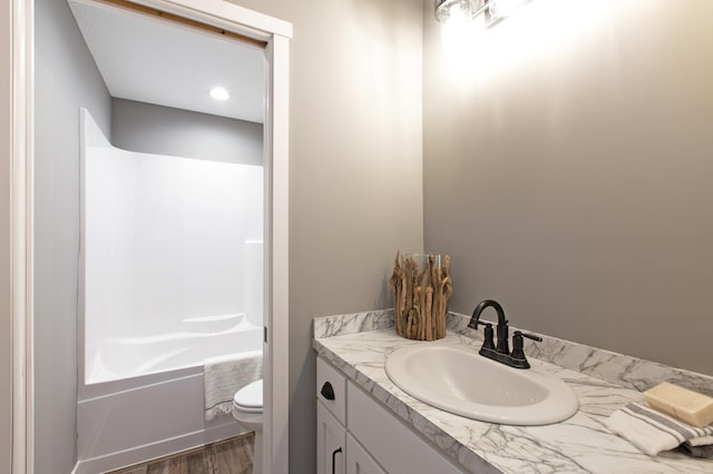 full bathroom with toilet, washtub / shower combination, vanity, and wood-type flooring