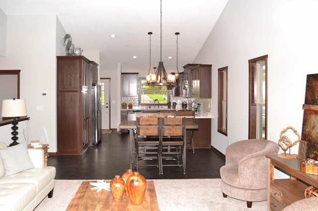 living room with an inviting chandelier, sink, dark wood-type flooring, and high vaulted ceiling