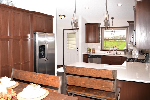 kitchen featuring decorative backsplash, sink, appliances with stainless steel finishes, a textured ceiling, and kitchen peninsula