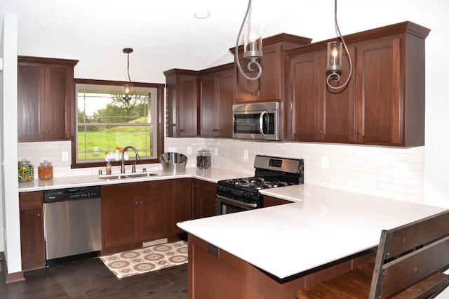 kitchen featuring tasteful backsplash, stainless steel appliances, pendant lighting, sink, and kitchen peninsula