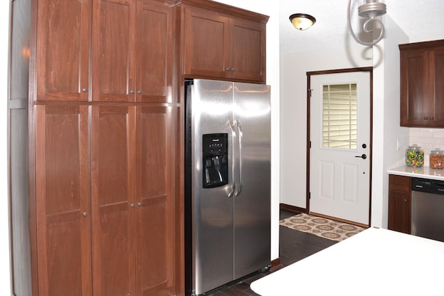 kitchen with appliances with stainless steel finishes, a textured ceiling, dark hardwood / wood-style flooring, and backsplash