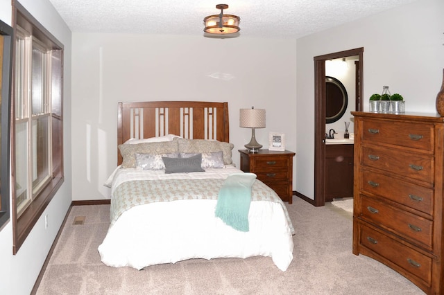 bedroom featuring light carpet, ensuite bathroom, a textured ceiling, and sink