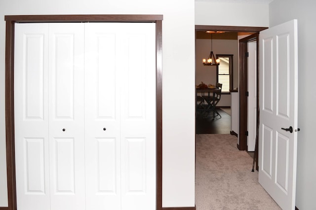 corridor featuring an inviting chandelier and light colored carpet