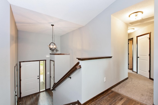 carpeted entryway with a notable chandelier and vaulted ceiling