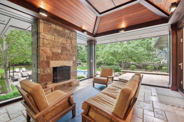 sunroom / solarium featuring vaulted ceiling, wood ceiling, and an outdoor stone fireplace