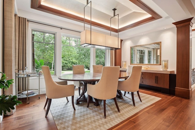 dining space with dark hardwood / wood-style flooring, decorative columns, and a raised ceiling