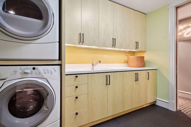 clothes washing area featuring sink, stacked washing maching and dryer, and cabinets