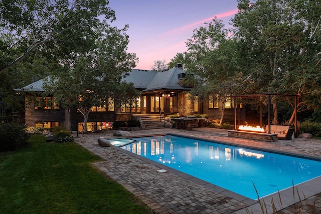 pool at dusk featuring a yard, a patio area, and a fire pit