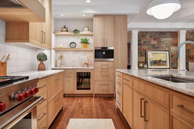 kitchen featuring a sink, stainless steel appliances, premium range hood, light stone countertops, and open shelves