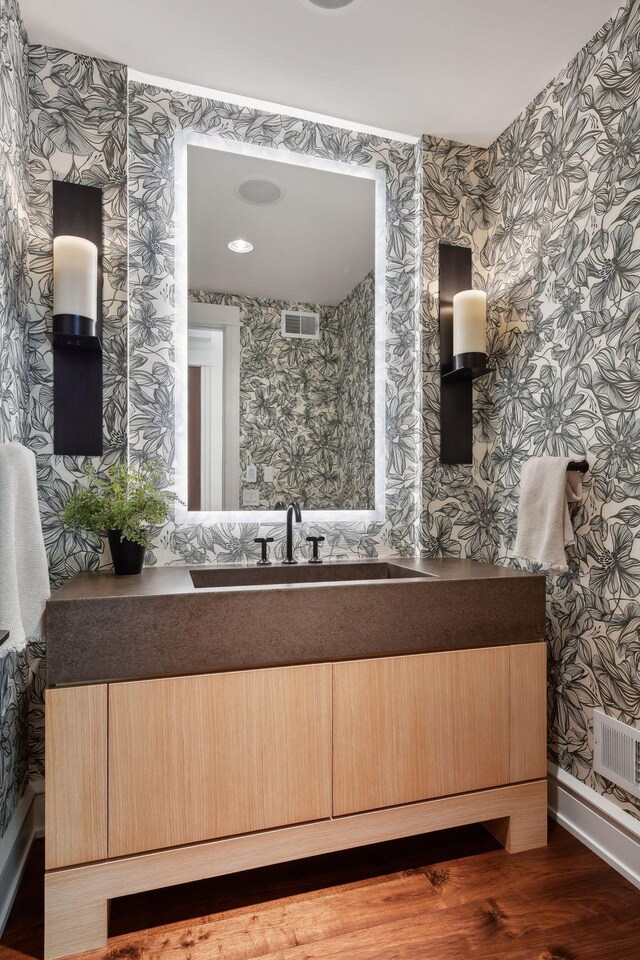 bathroom featuring wallpapered walls, wood finished floors, and vanity